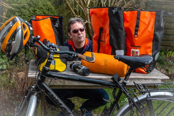 Mensch hockt hinter leeren Fahrradtaschen und packt.